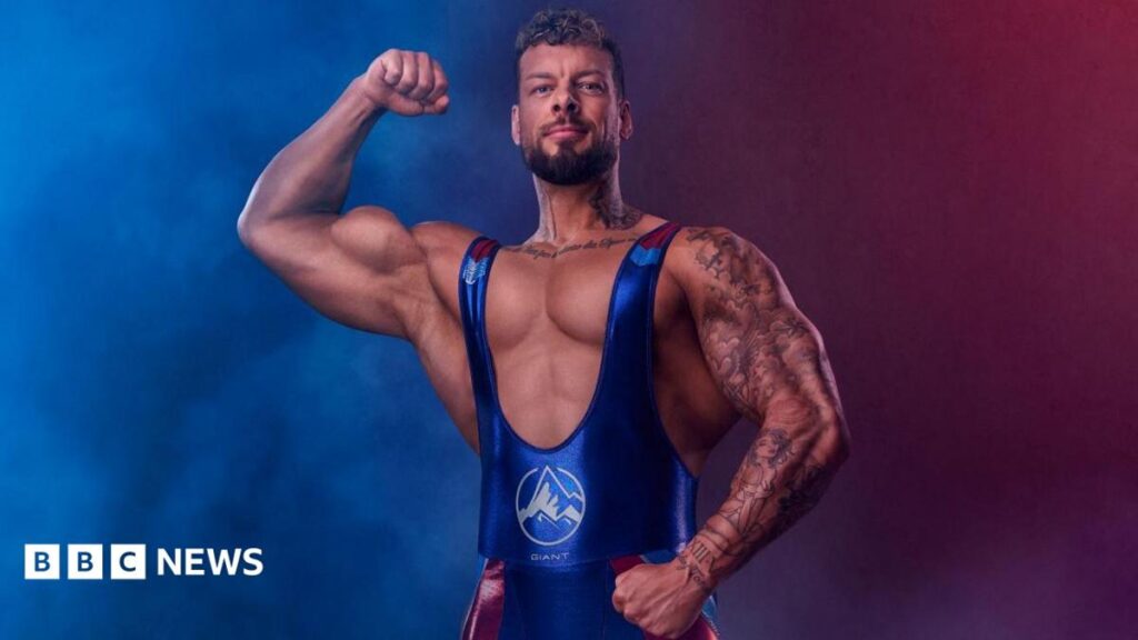 Giant considers next steps after Gladiators exit A man with extremely large biceps flexes his muscles in a blue and red leotard.