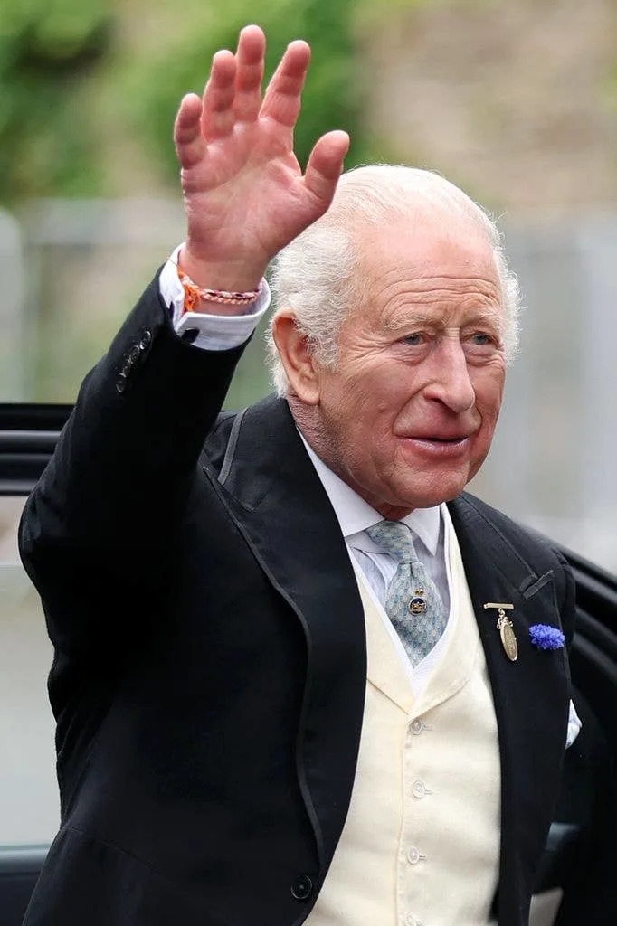 King Charles III waves as he arrives for the Royal wedding of Peter Phillips and Harriet Sperling at All Saints' Church