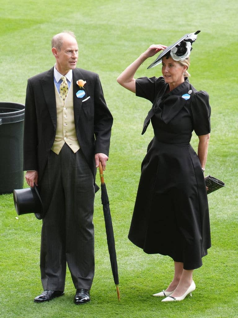 The Duchess of Edinburgh in a black dress holding onto her hat at Royal Ascot