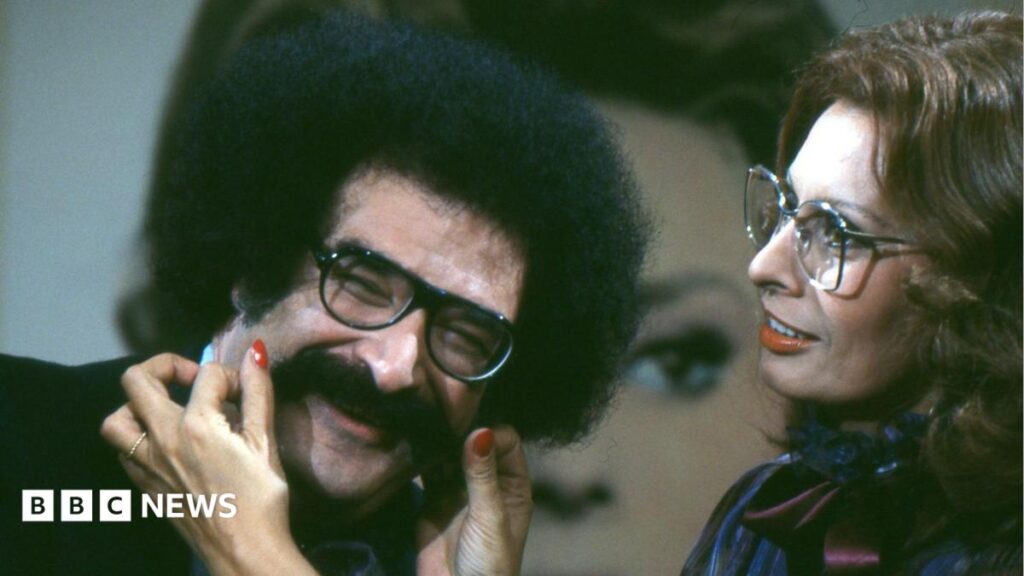 Gene Shalit, popular US movie critic, has died aged 100 Faisal Islam wearing a dark blue jumper with 3 lions written on it in red.