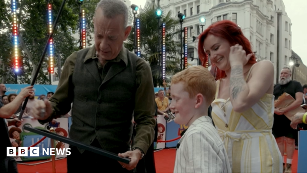 Tom Hanks congratulates Blackpool boy, 8, on Toy Story 5 artwork A young girl with brown hair sat in a chair. She's facing a reporter who is holding a mic to her face.