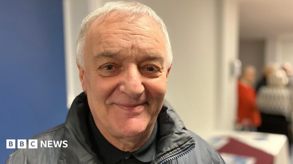 Football legend Macari and DJ Bowie among Scots honoured by King Lou Macari, a man with grey hair, is wearing a black leather jacket and a black shirt. He is standing in a well-lit room with a group of people in the background.