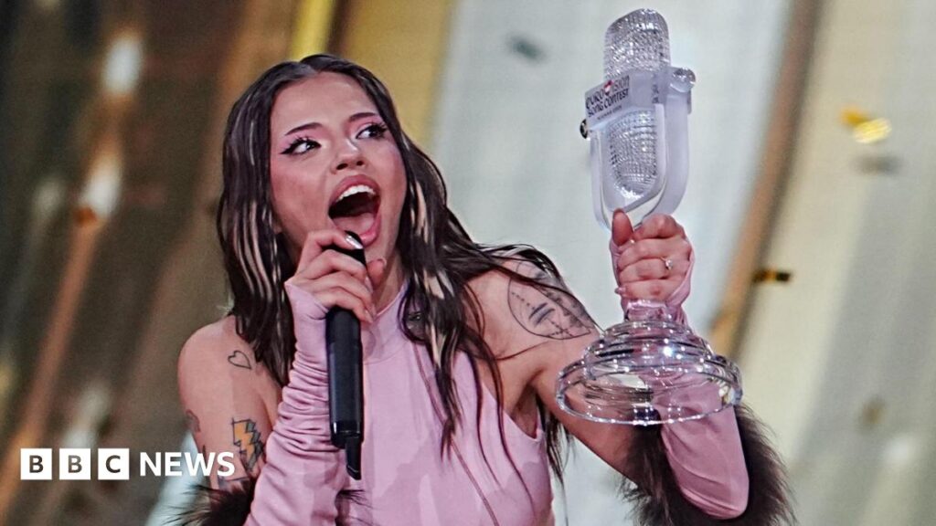 Dara: Bangaranga singer says she almost quit Eurovision Dara is holding Eurovision's glass microphone trophy after winning the competition in Vienna in May. She is wearing a pink top with her shoulders uncovered, showing several tattoos. She has blonde highlights in her otherwise dark hair and is open-mouthed with excitement. She has pink eyeshadow with dark eyeliner and thick eyelashes. She is talking into a black microphone.
