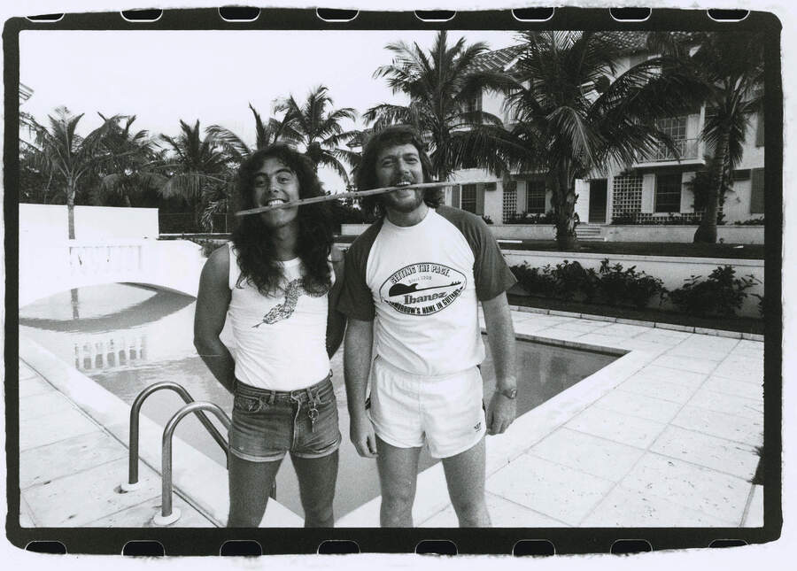 Steve Harris and Maiden manager Rod Smallwood with a drumstick in their mouths in the Bahamas.