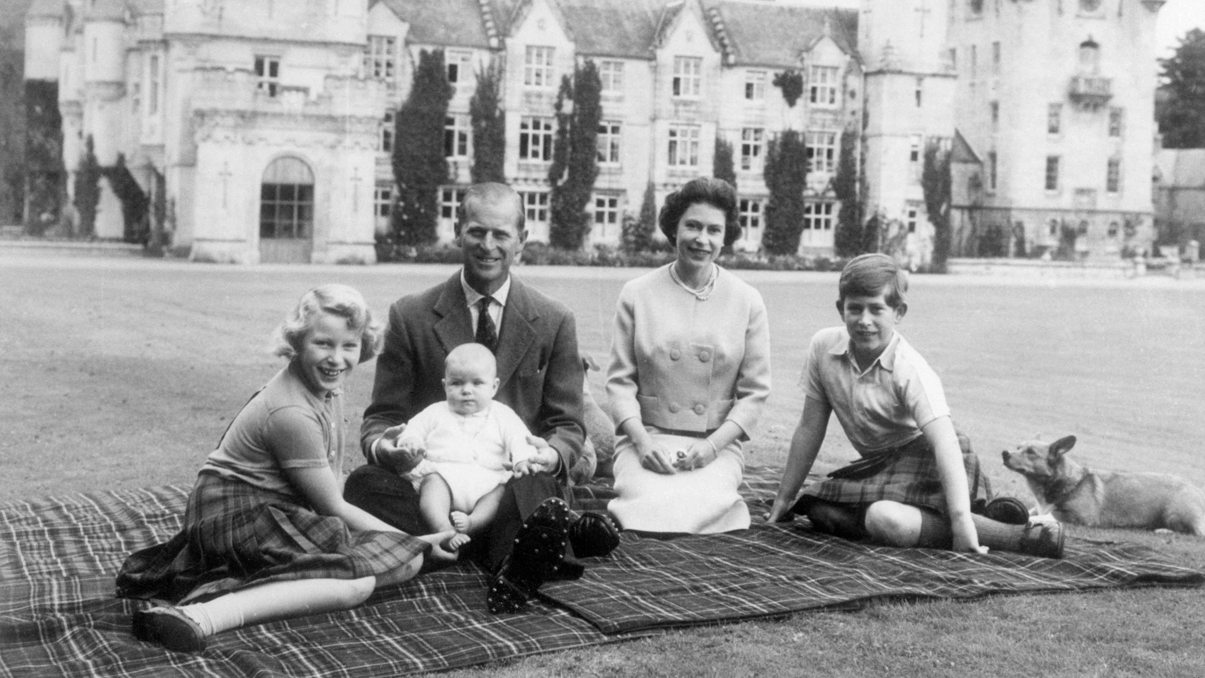 Queen Elizabeth II and Prince Philip with their children, Andrew (centre), Anne (left) and Charles, sitting on a picnic rug outside Balmoral Castle in Scotland, 8th September 1960
