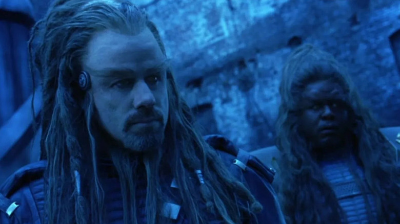 Terl (John Travolta) and Ker (Forest Whitaker) stand in a blue filtered canyon in Battlefield Earth