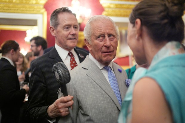 Charles is cooled by senior aide Vice Admiral Sir Tony Johnstone Burt at the London event.