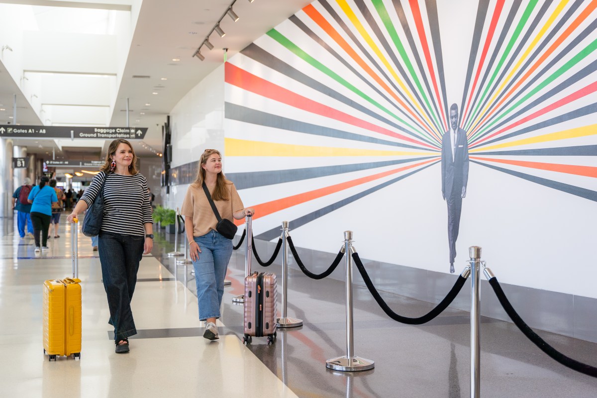 two women walking at Birmingham-Shuttlesworth International Airport admiring an art installation 