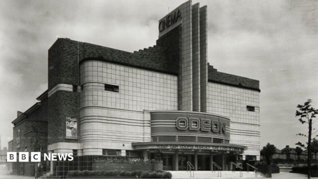 Call to save ‘striking’ Birmingham Art Deco building. An Odeon building which has an Art Deco structure with rounded corners and horizontal lines. There is a central tower rising above the entrance with horizontol straight lines. At the bottom “ODEON” is displayed. There are steps leading up to the doors.