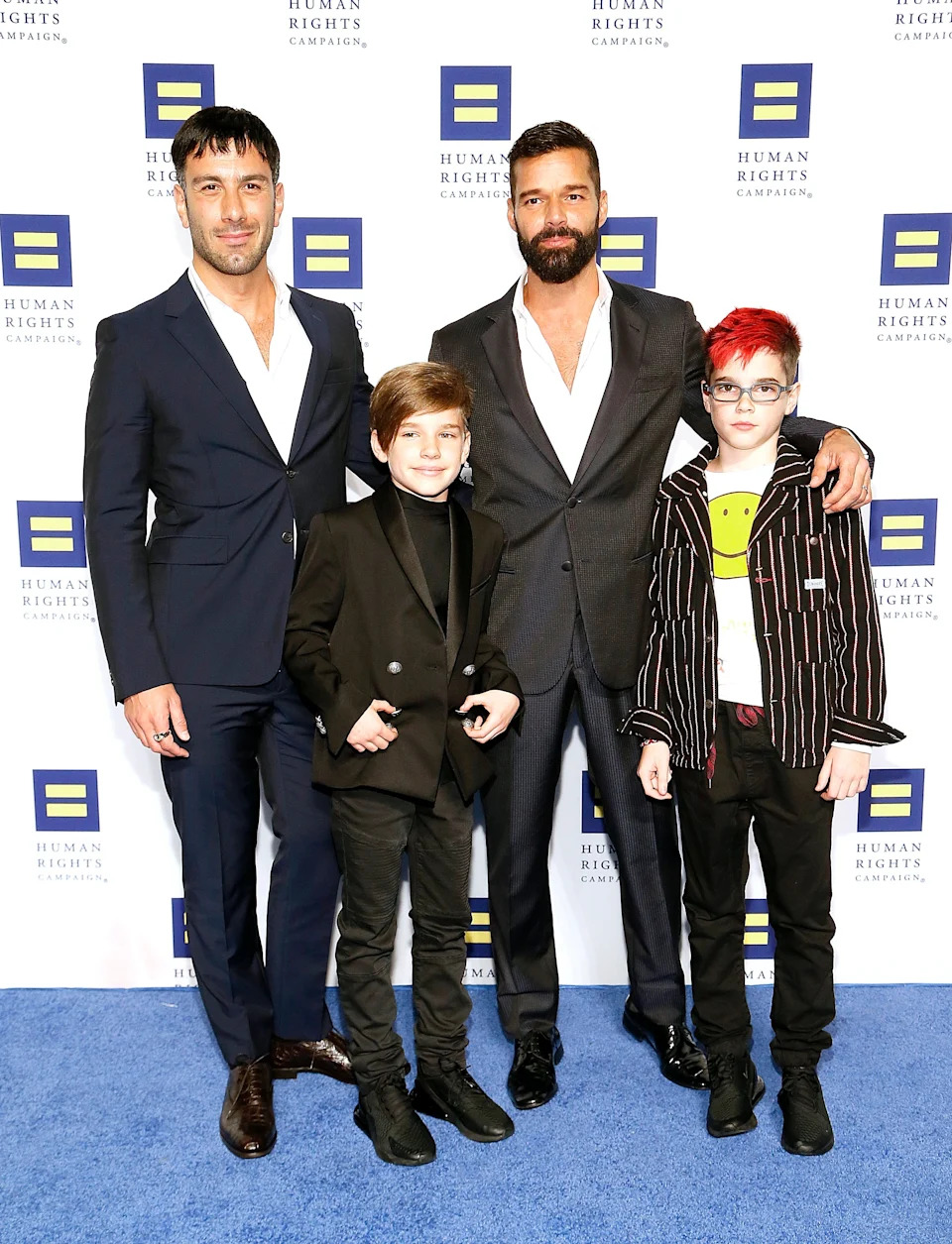 Four people in formal and casual clothes pose together at a Human Rights Campaign event. One adult wears a suit, another a blazer; two children are with them