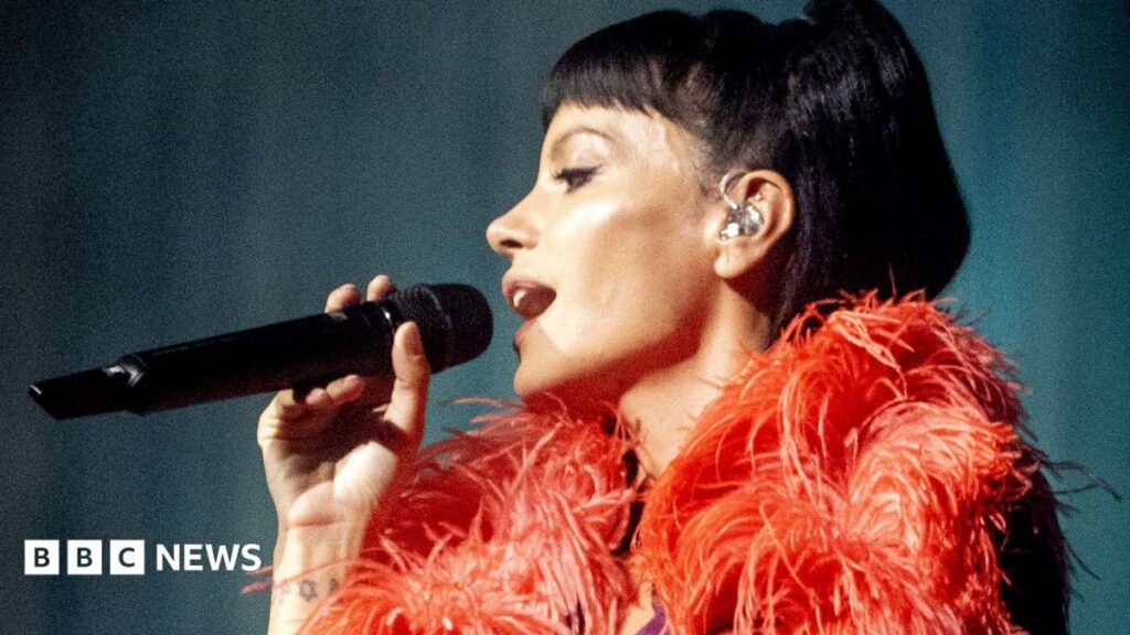 Lily Allen defends West End Girl tour after some fans criticise show length A woman in a pink bikini lies on a deck chair covered in pink blankets, reads a magazine. there are pink towels, a tote bag and a radio next to her.