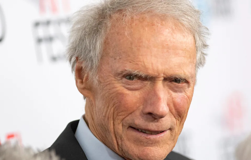 Clint Eastwood with short hair, wearing a suit, poses at a formal event