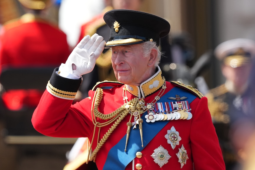 The king in traditional dress salutes.
