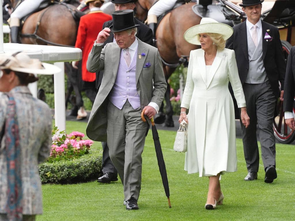 Queen Camilla wears a white dress, hat and bag