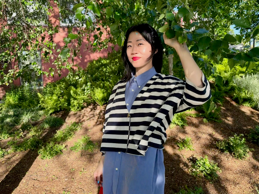 mary hk choi smiling under a tree in a striped sweater.