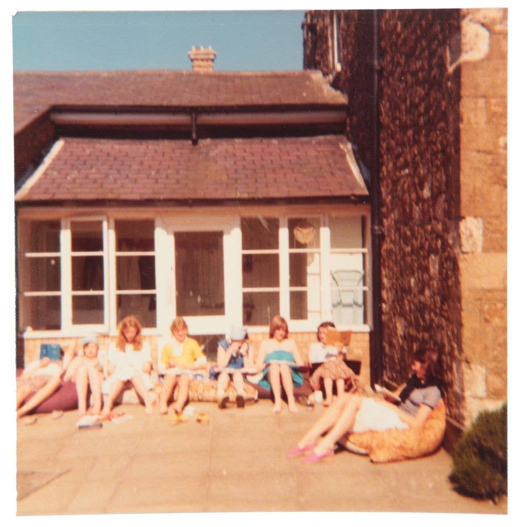 A group of pupils (including Diana) are seen relaxing outside in the sun against the school building at West Heath Girls' School
