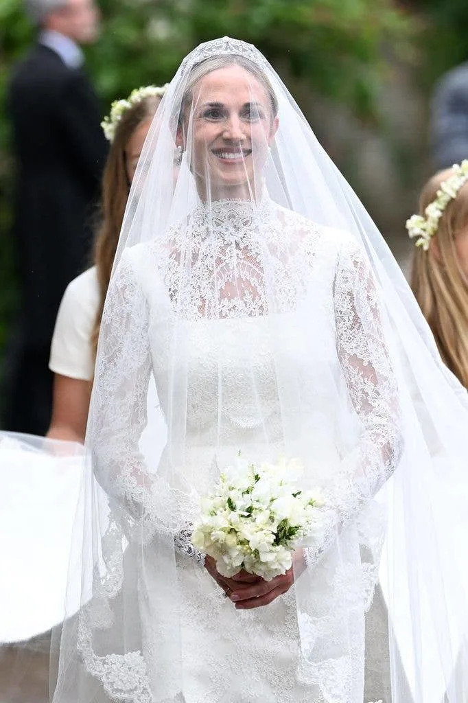 Harriet Sperling smiling wearing a bridal gown and holding flowers