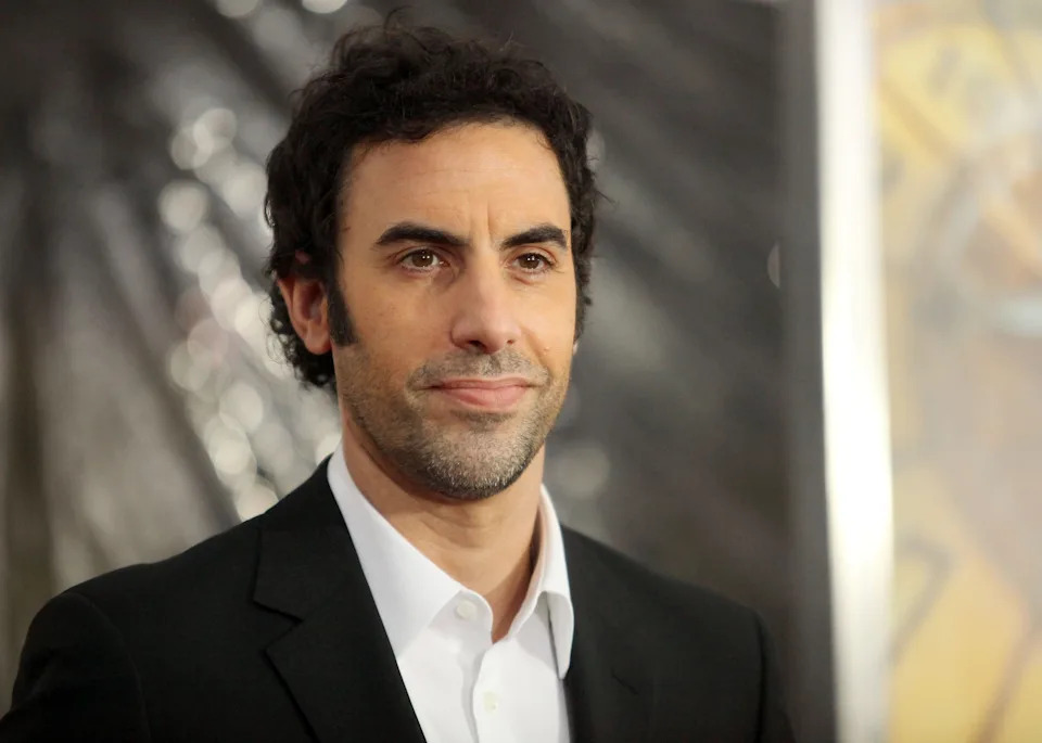 A person in a suit poses on a red carpet at a celebrity event