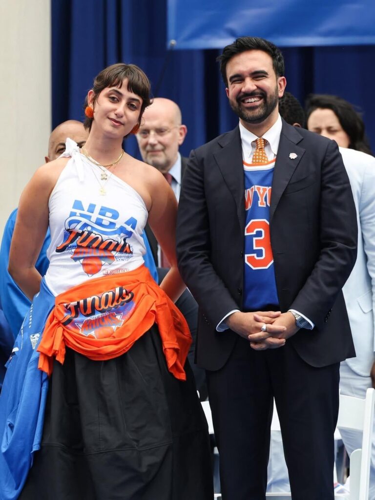 NYC’s First Lady Rama Duwaji wore a custom look by designer Miss Claire Sullivan at the Knicks City Hall ceremony this afternoon. The up-cycled one-shoulder dress was comprised of three different bootleg Finals merch stitched together. (June 18, 2026) NYC’s First Lady Rama Duwaji wore a custom look by designer Miss Claire Sullivan at the Knicks City Hall ceremony this afternoon. The up-cycled one-shoulder dress was comprised of three different bootleg Finals merch stitched together. (June 18, 2026)