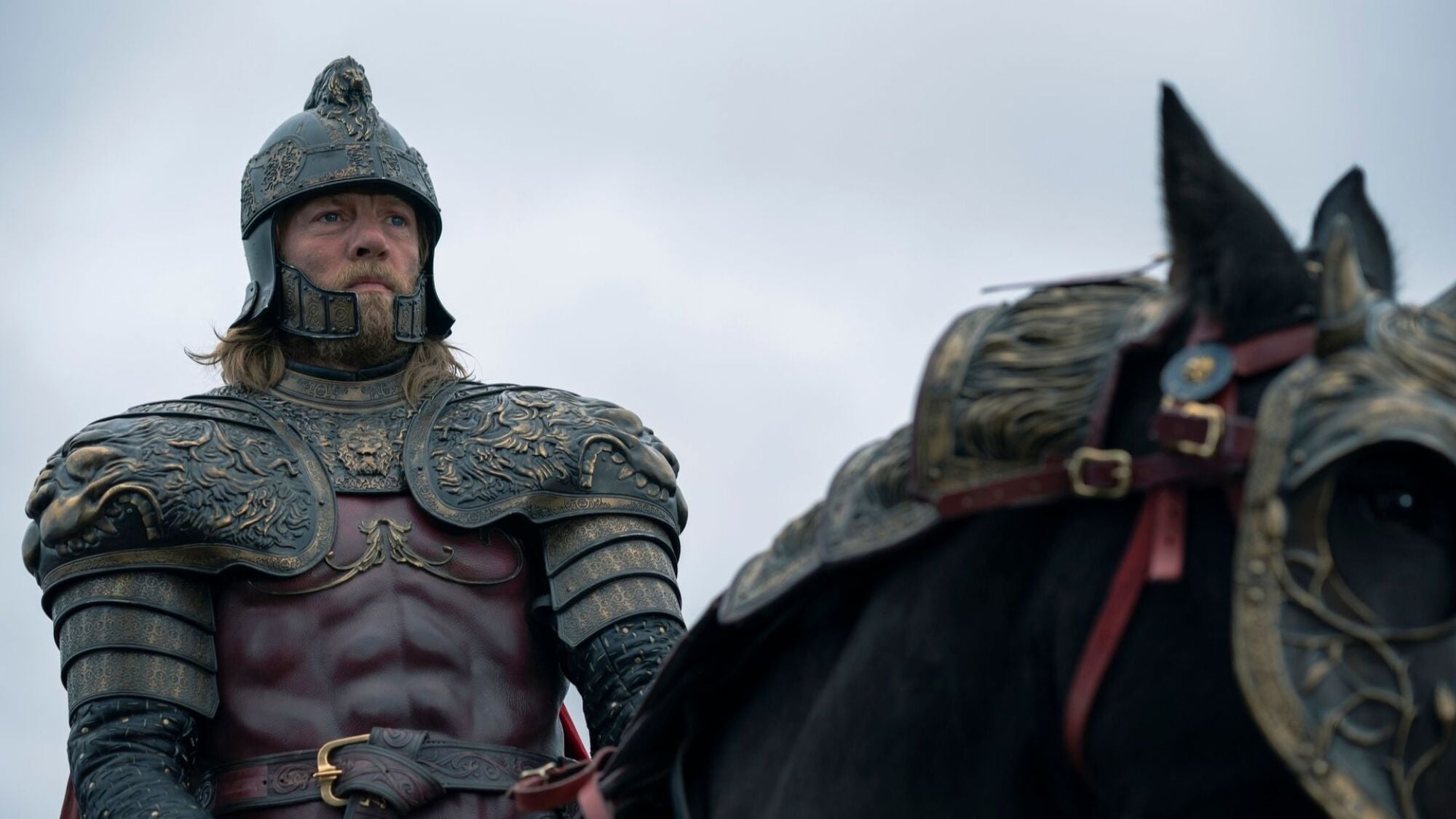 A man in armour sits on top of a horse.