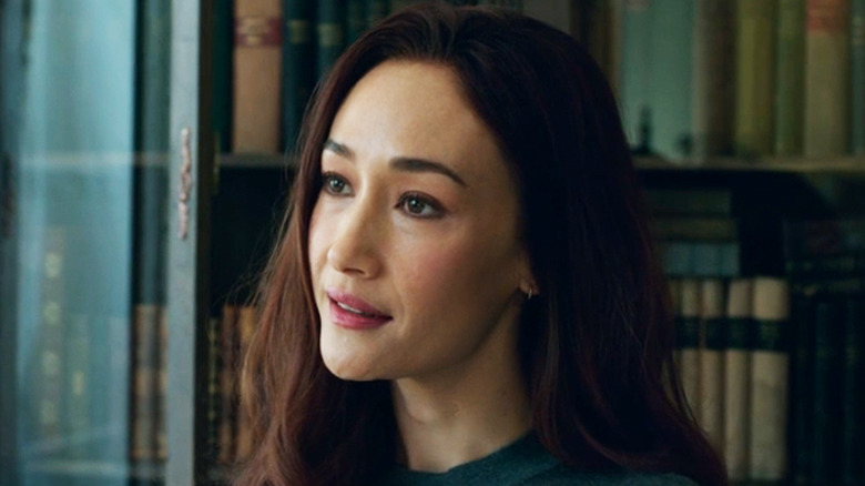 Maggie Q's Anna Dutton smiles as she stands in front of a shelf of books in The Protégé