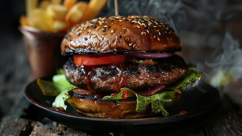 Juicy grilled burger on plate with tomato and lettuce toppings