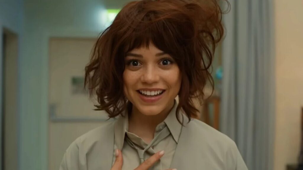 pretty brunette humanoid with tousled hair smiling into the camera, one hand on her chest as if to say "This is me"