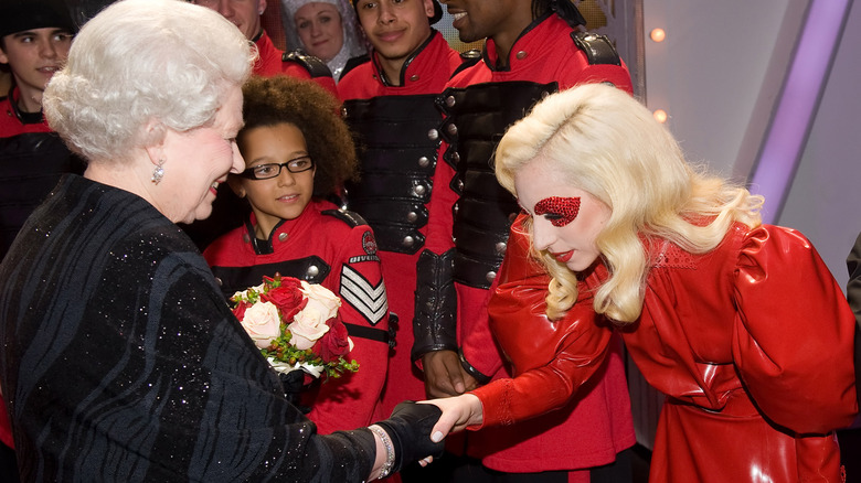 Lady Gaga bowing her head as she shakes Queen Elizabeth II's hand