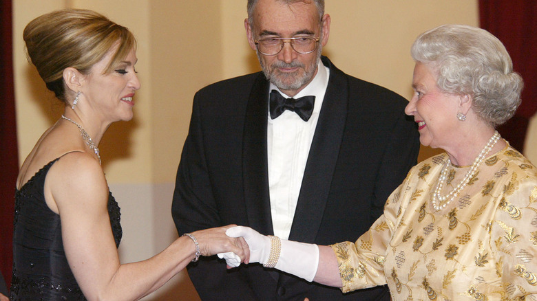 HRH Queen Elizabeth II meets pop star Madonna (L) watched by producer Michael Wilson at the World premiere of Bond movie "Die another Day" at London's Albert Hall on November 18th, 2002