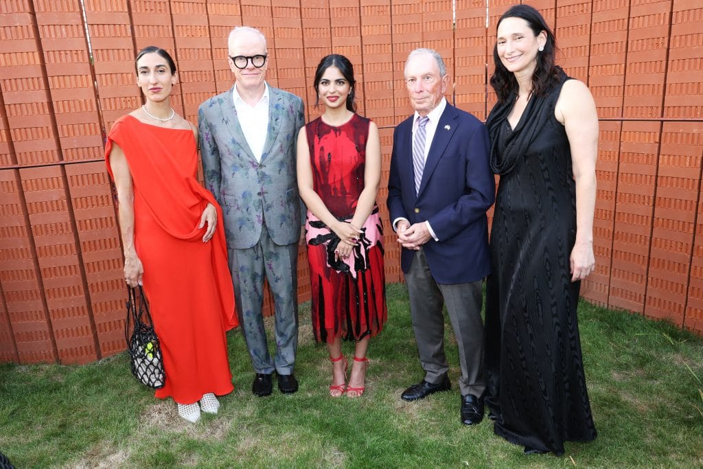 five people pose for the camera at the Serpentine Summer Party, in front of a red brick wall
