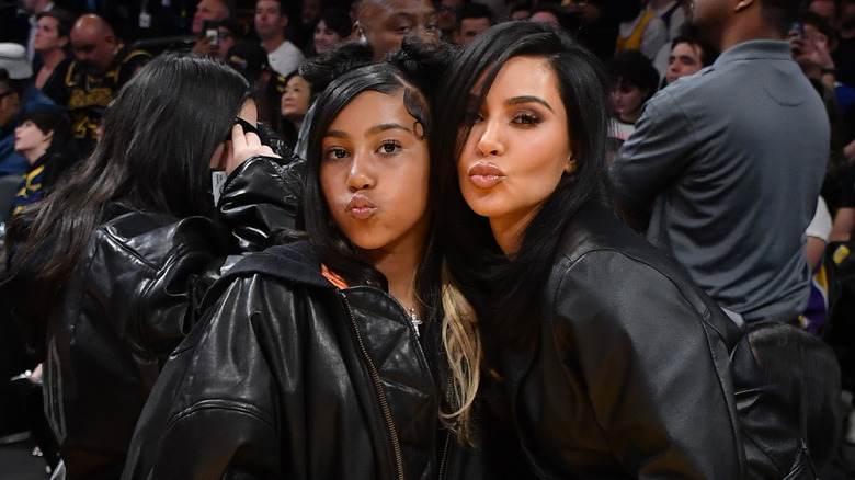 North West posing with mother Kim Kardashian making duck faces while wearing all-black outfits.