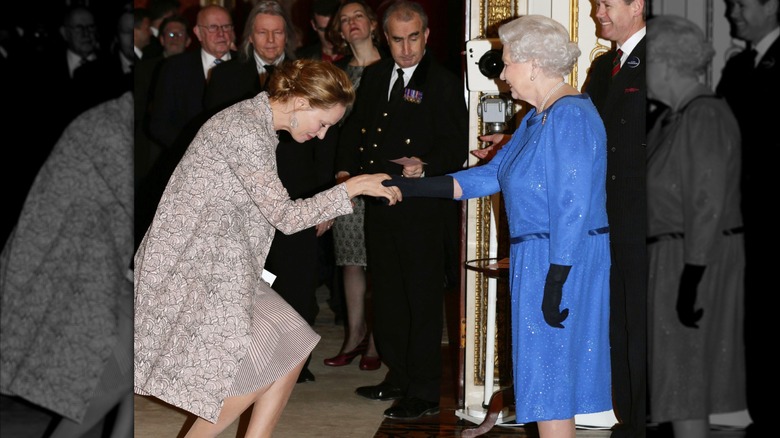 Uma Thurman curtsying to Queen Elizabeth at the Dramatic Arts reception at Buckingham Palace on February 17, 2014