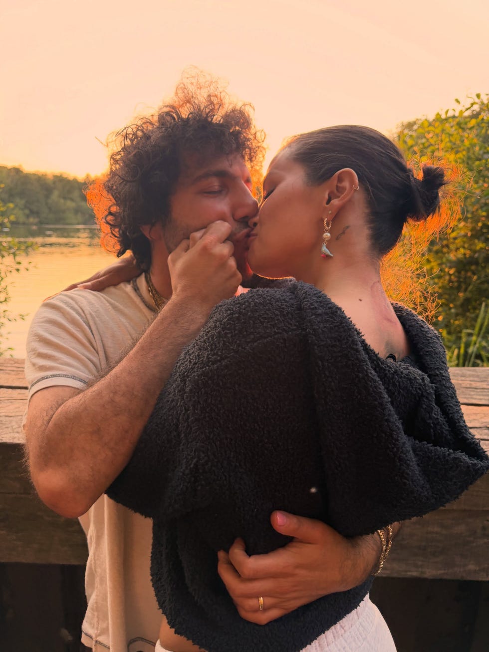 A couple sharing a romantic kiss at sunset by a lakeside, surrounded by nature. A couple sharing a romantic kiss at sunset by a lakeside, surrounded by nature.