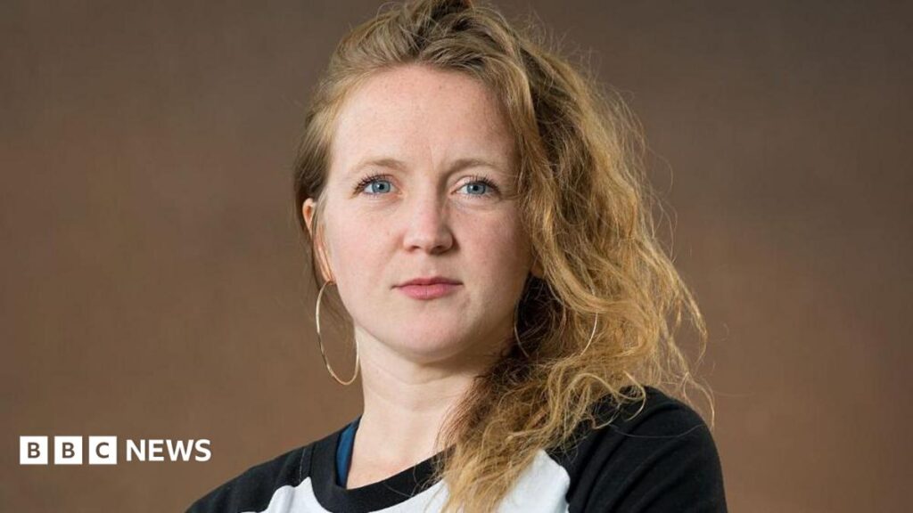 Hollie, wearing a black and white top, smiles at the camera