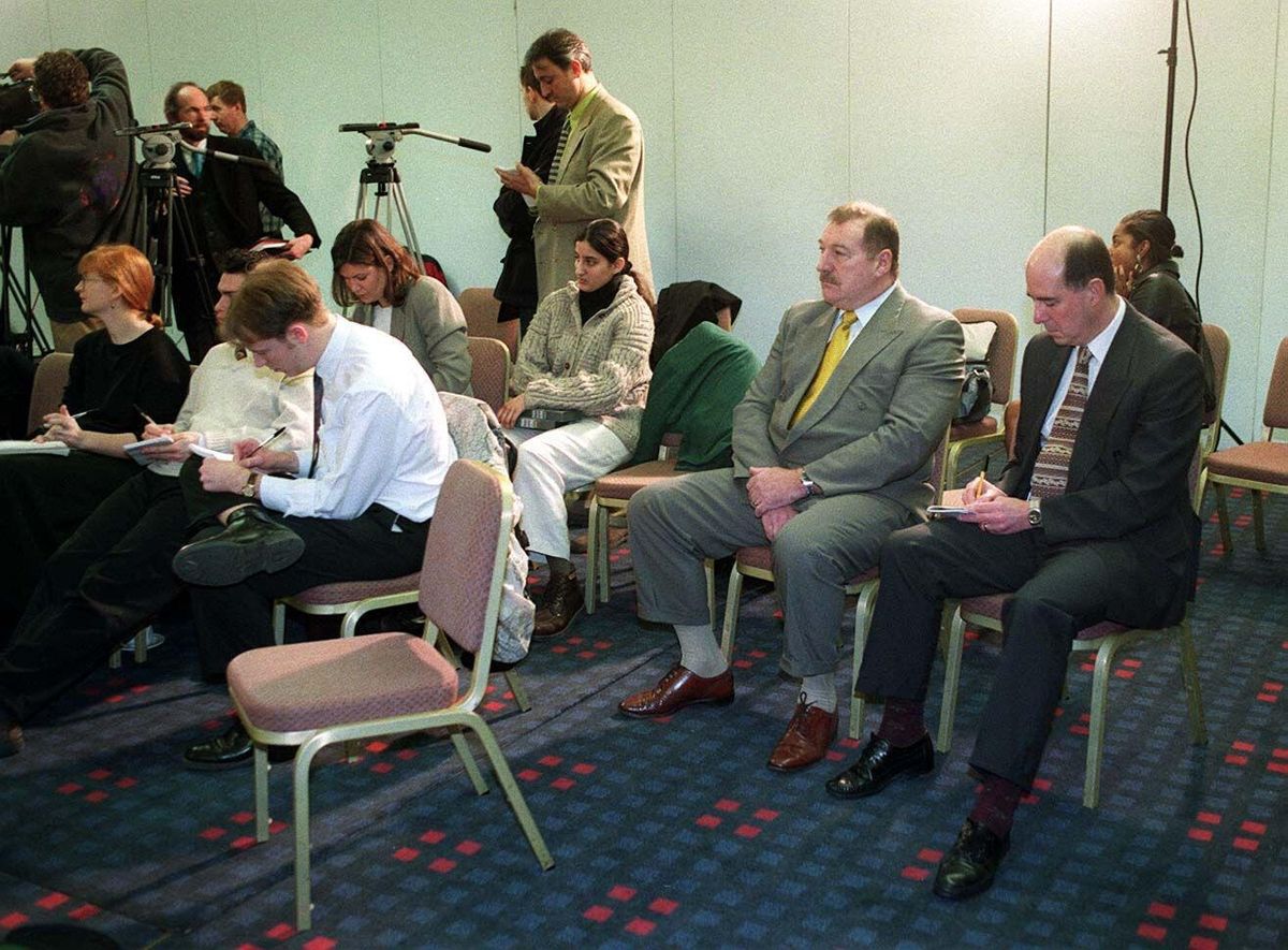 Ian Johnston sits with the media as he watches Tracie Andrews at the press conference