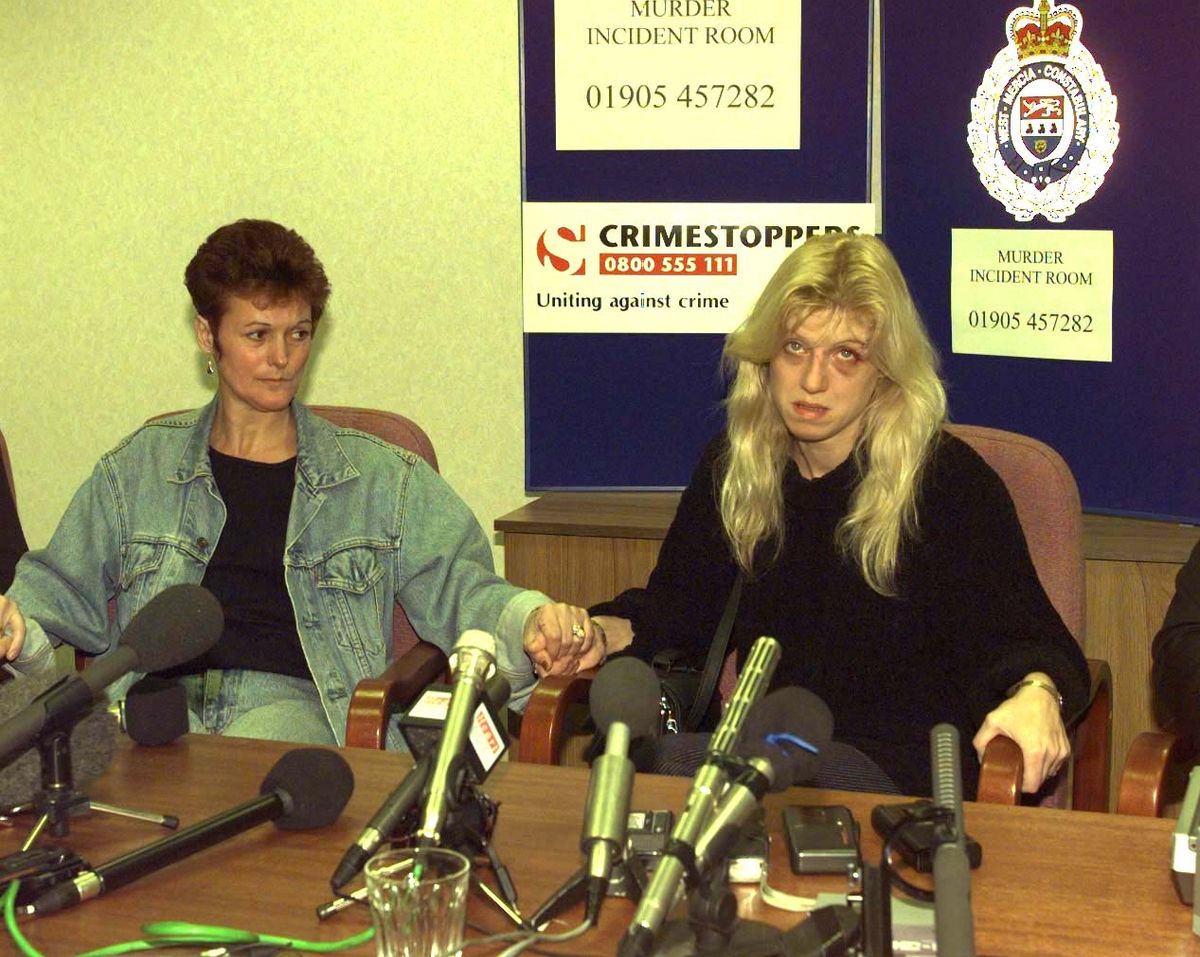Tracie Andrews holds the hand of Maureen Harvey, the mother of her victim as she lies to the media