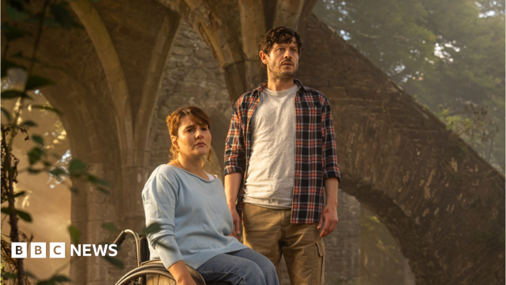 Ruth Madeley and Iwan Rheon in the new TV drama series. They both look concerned and are inside the ruins of an old building with trees behind.