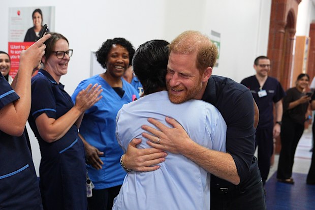 Prince Harry, Duke of Sussex, Patron of WellChild, embraces a nurse as he arrives for a visit to the Birmingham Children’s Hospital