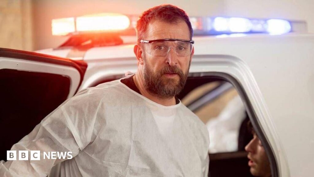 Emmy Awards nominations 2026: See the key categories in full Noah Wyle in PPE glasses and shirt, in front of an ambulance with blue and orange lights flashing, in a scene from The Pitt