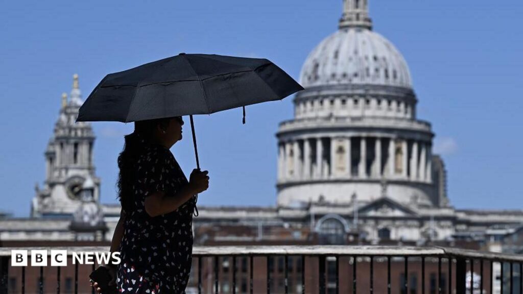 UK heatwave: Heat health alerts extended as temperatures expected to peak A woman walks under an umbrella past St Paul's Cathedral in London during the heatwave.