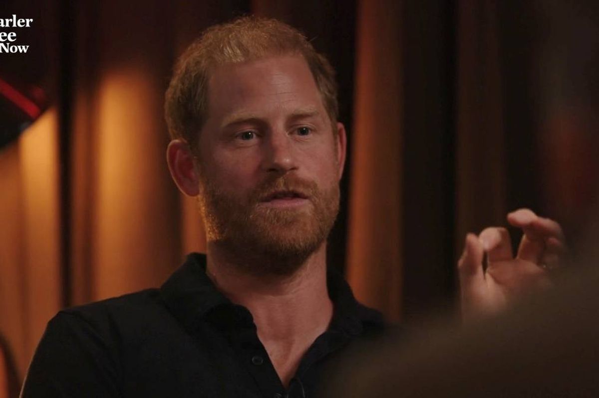 An adult male, dressed in a black shirt, is engaged in a conversation, with his expression focused and intent. He is situated in an interior space adorned with warm lighting and textured backdrops, contributing to a contemplative atmosphere.
