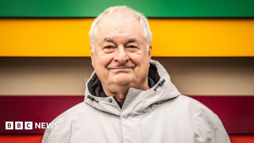 BBC radio DJ Paul Gambaccini diagnosed with Alzheimer’s Paul Gambaccini stood in front of a green, yellow and red background.