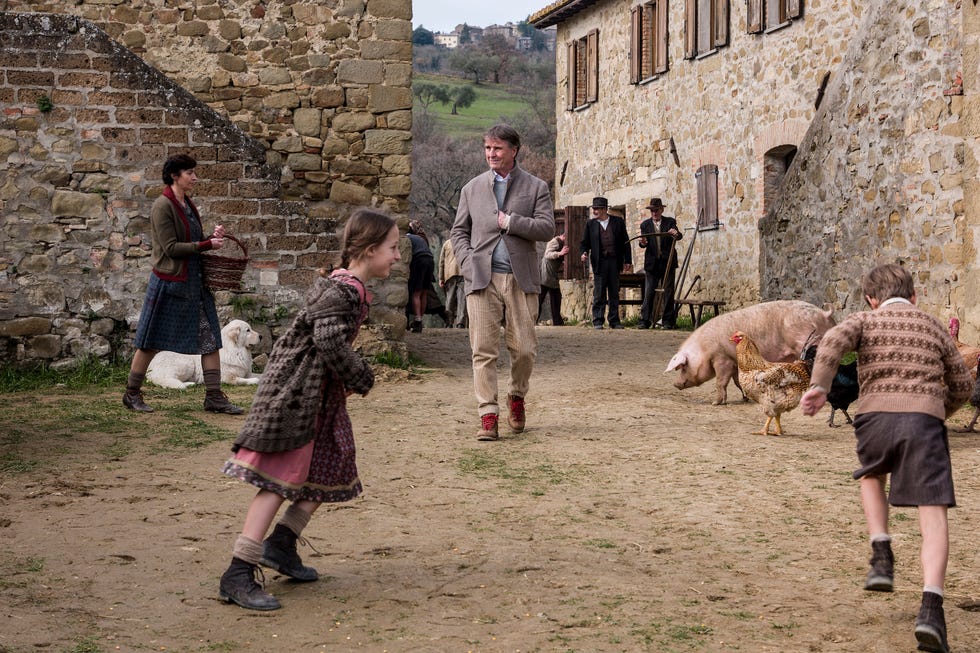 Children playing in a rustic farm setting with animals and adults engaged in various activities. Children playing in a rustic farm setting with animals and adults engaged in various activities.