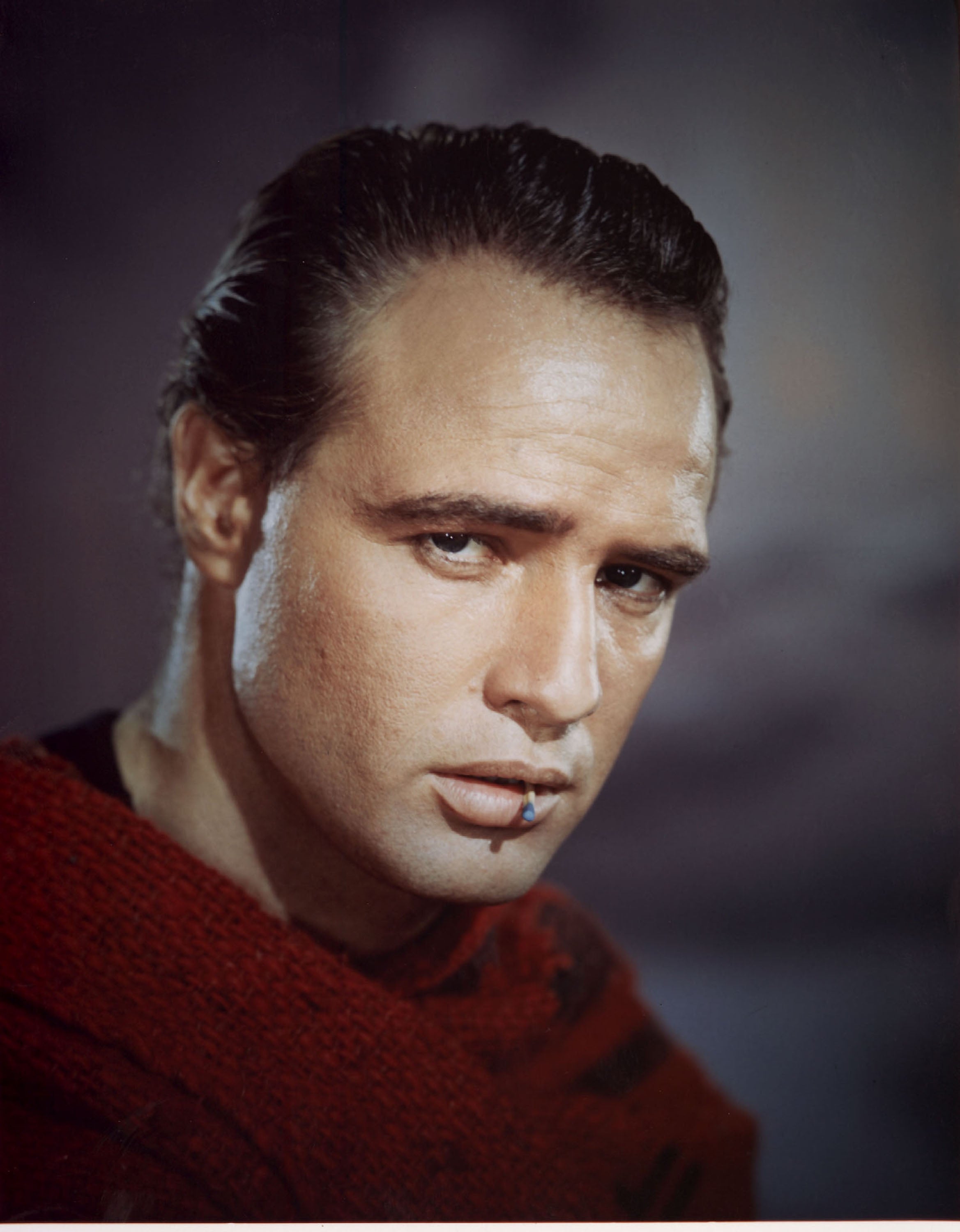 Person with slicked-back hair and contemplative expression, wearing a textured garment