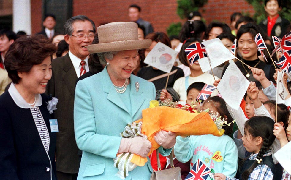 britains queen elizabeth ii holds a bouquet of flowers in seoul 19 april 1999, as flag waving south korean children greet her at midong elementary school. queen elizabeth and her husband prince philip arrived in seoul on the first visit to south korea by a british monarch since ties were established in 1883. afp photo (photo by yun suk bong / rtr pool / afp) (photo by yun suk bong/rtr pool/afp via getty images)