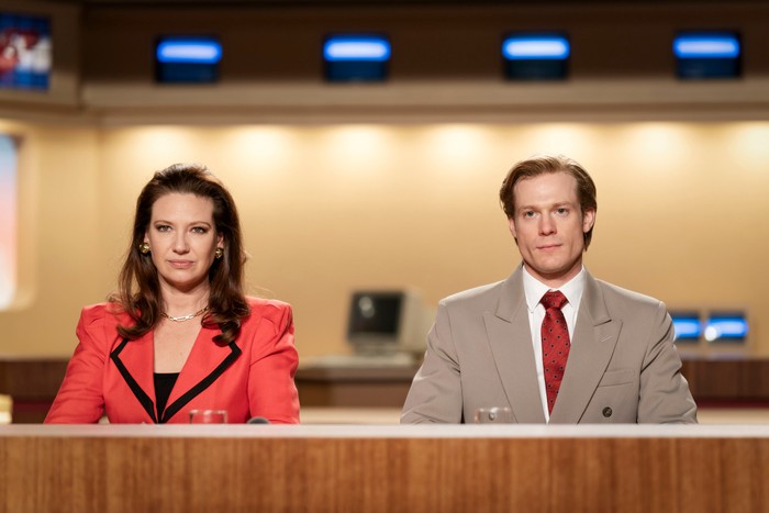 Anna Torv as Helen Norville and Sam Reid as Dale Jennings in The Newsreader sat at a desk
