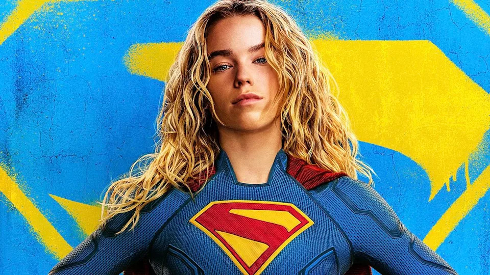 Supergirl in costume in front of blue and yellow logo in Supergirl poster.