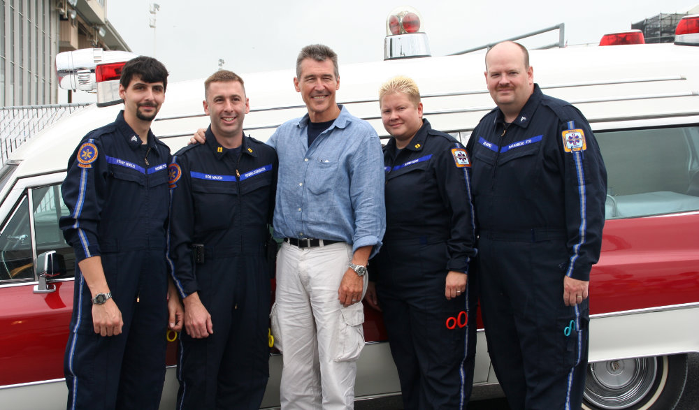 a group of men standing in front of an ambulance.