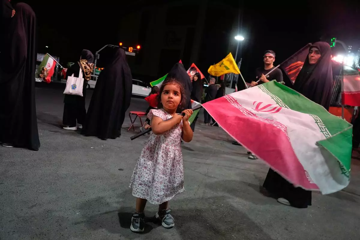 A girl waves an Iranian flag in a pro-government gathering commemorating the late Iranian Supreme Leader Ayatollah Ali Khamenei at a square in Tehran, Saturday, July 11, 2026. (AP Photo/Vahid Salemi)