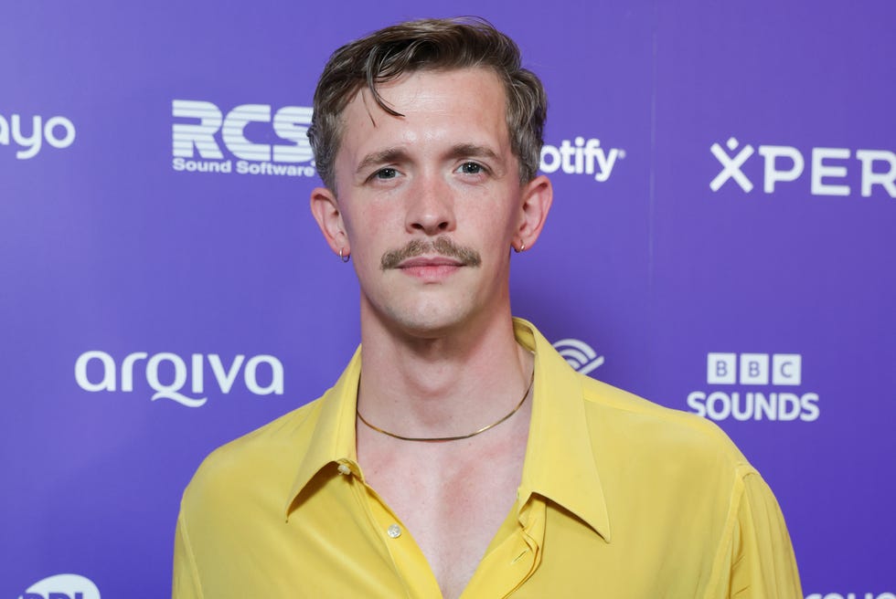 stephen libby wearing a yellow shirt and standing against a purple branded backdrop